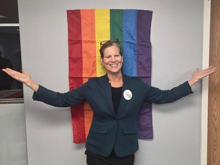 Victoria Doyle in front of a rainbow Pride flag
